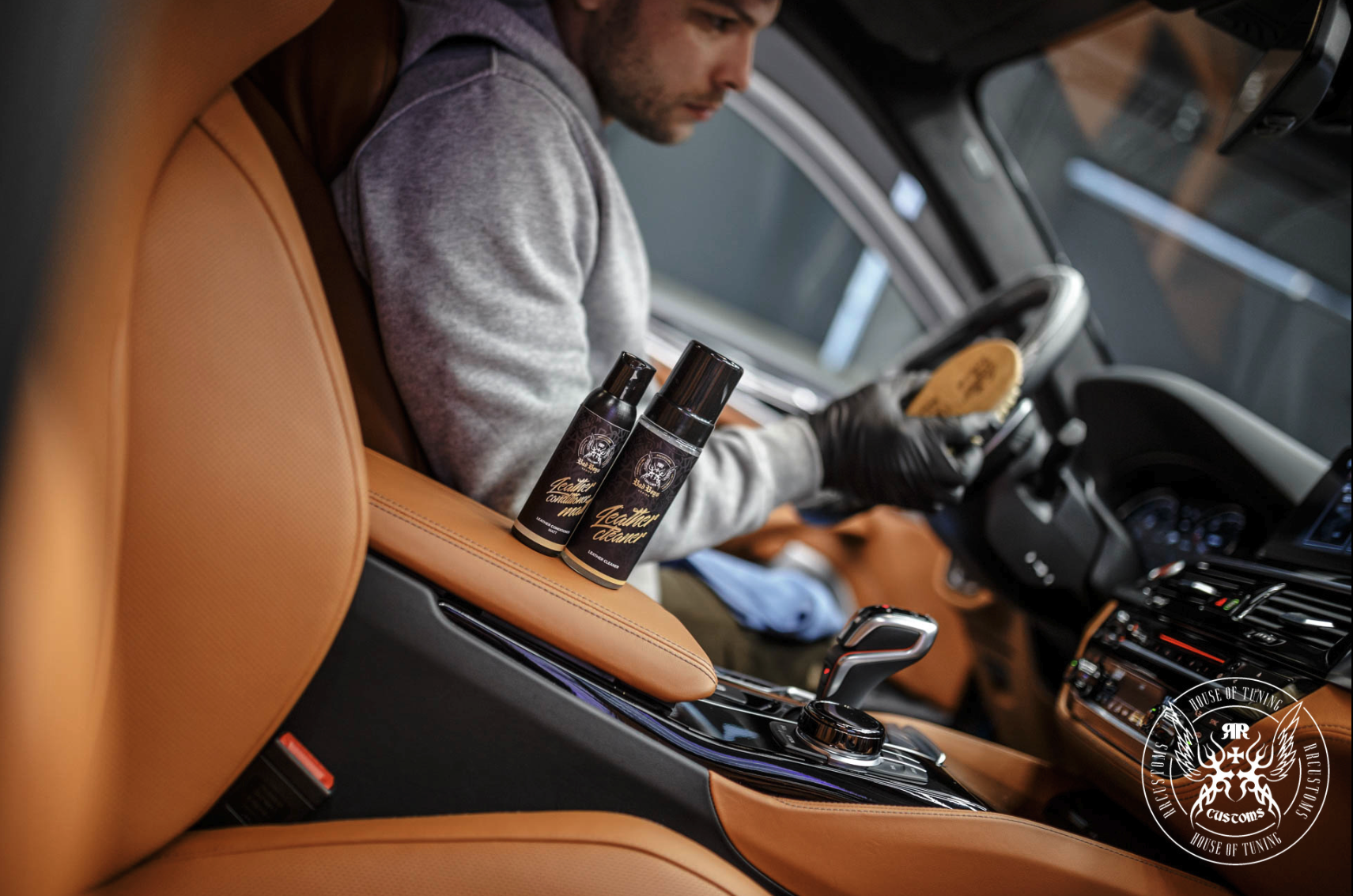 Leather Care Set – Detailer em jaqueta cinza a aplicar produto com escova em luxuoso assento de couro caramelo | Cuidado do Couro | miio Store