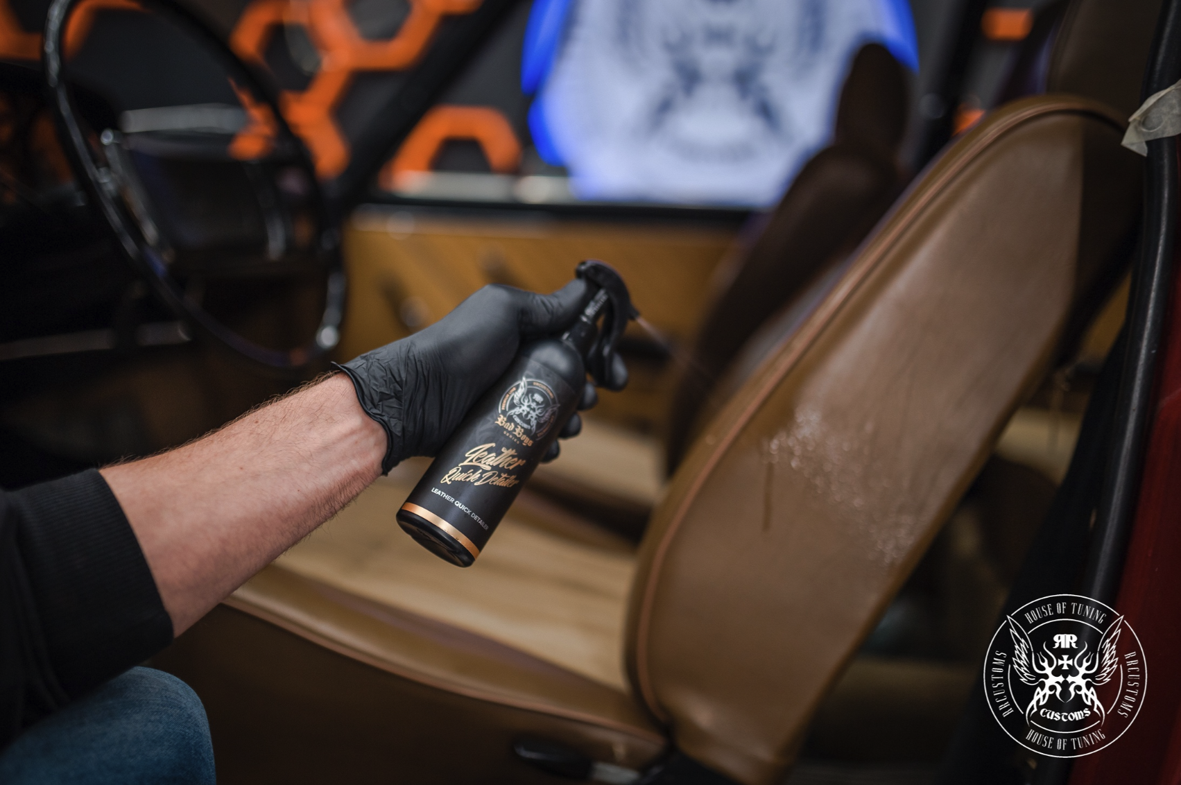 Leather Quick Detailer – Gros plan main gantée noire avec flacon près du cuir caramel, étiquette dorée visible | Soin Cuir | miio Store