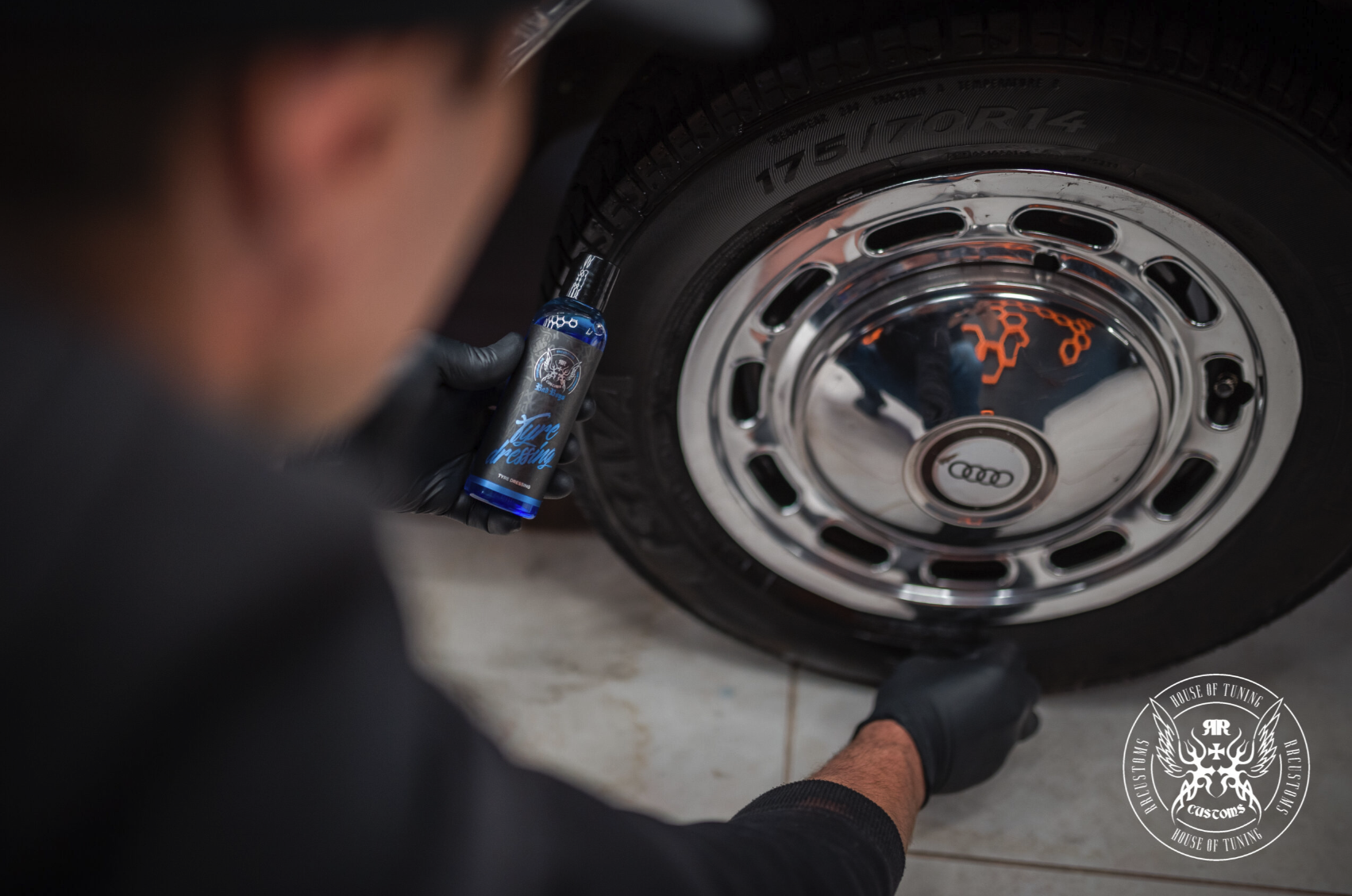Tyre Dressing 500ml – Persona aplicando tyre dressing en tapacubos cromado vintage, frasco azul visible, vista en ángulo bajo | Detailing Auto | miio Store