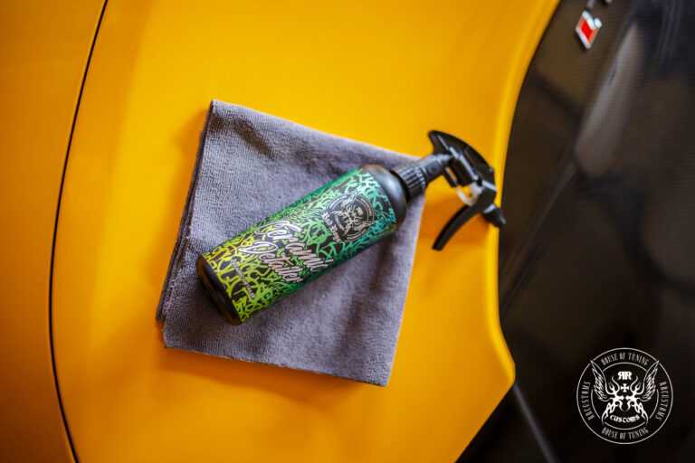 Ceramic Detailer 500ml – Frasco com rótulo verde apoiado em painel de porta de carro amarelo com pano de microfibra cinza | Detailing Auto | miio Store