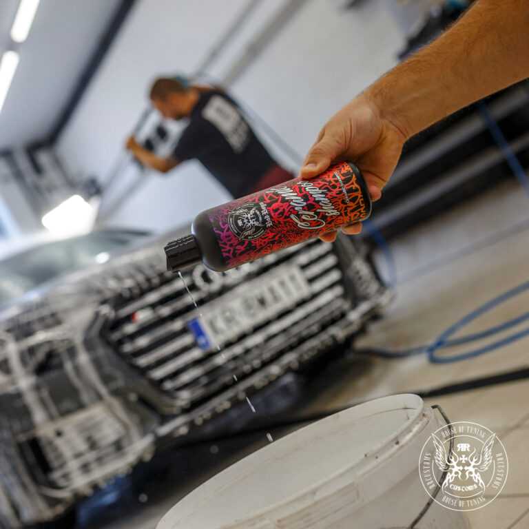 Ceramic Shampoo 500ml – Mano inclinando frasco para verter ceramic shampoo cerca de la rejilla delantera de un coche en garaje profesional | Lavado Auto | miio Store